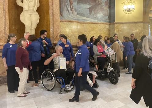 People smile and speak to each other in a large group while in the Topeka Capitol